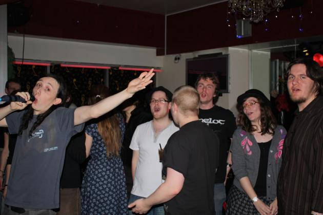 Chris and Nicola lead the society in a rendition of It's A Sin due to Rich's absence.
